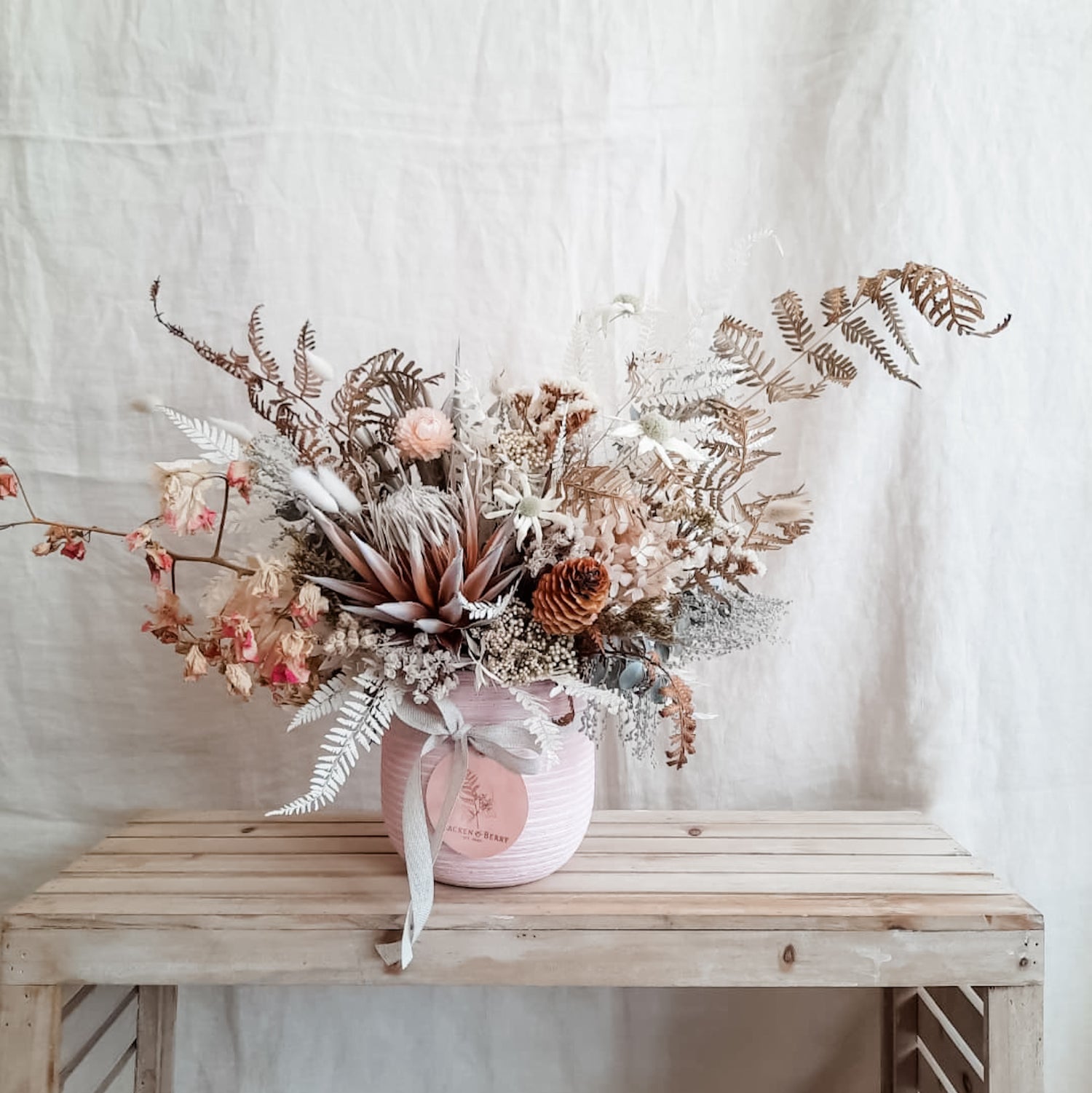 Dried flower arrangement in pink vessel.