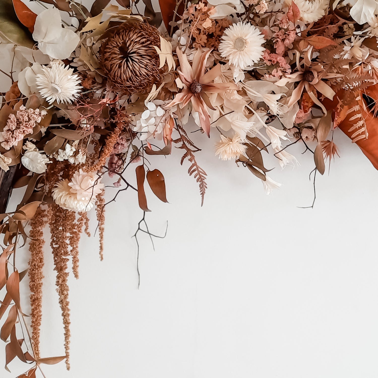 Close up of a dried flower wall hanging in earthy neutrals.