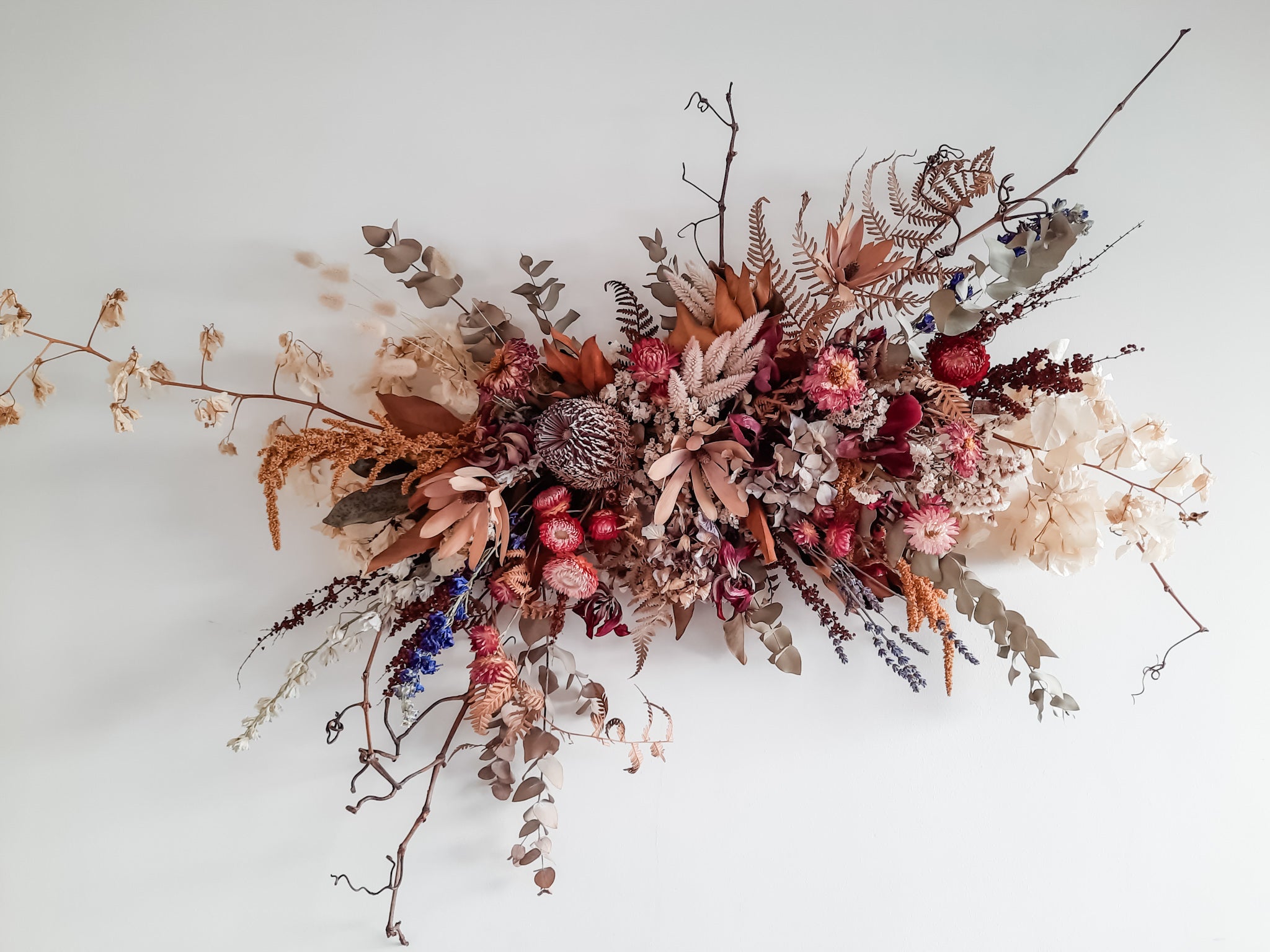 Dried flower wall hanging in rich berry tones.