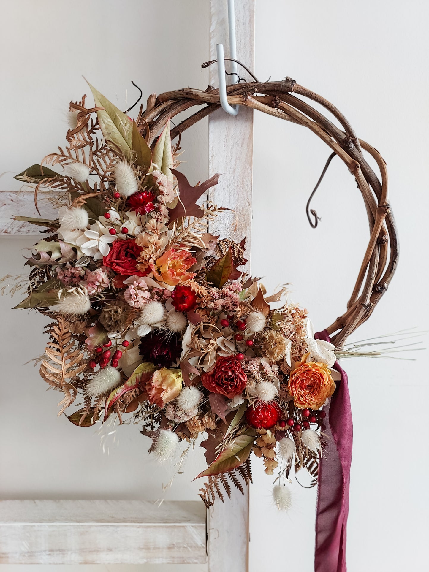 Dried flower wreath in rich autumnal tones on a grapevine base.