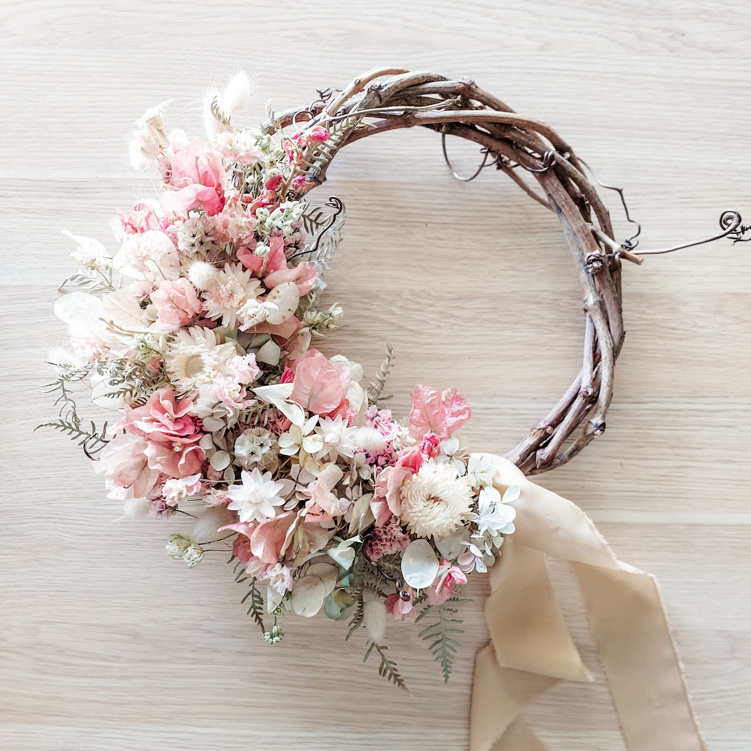Dried flower wreath in soft pastel tones on a grapevine base.
