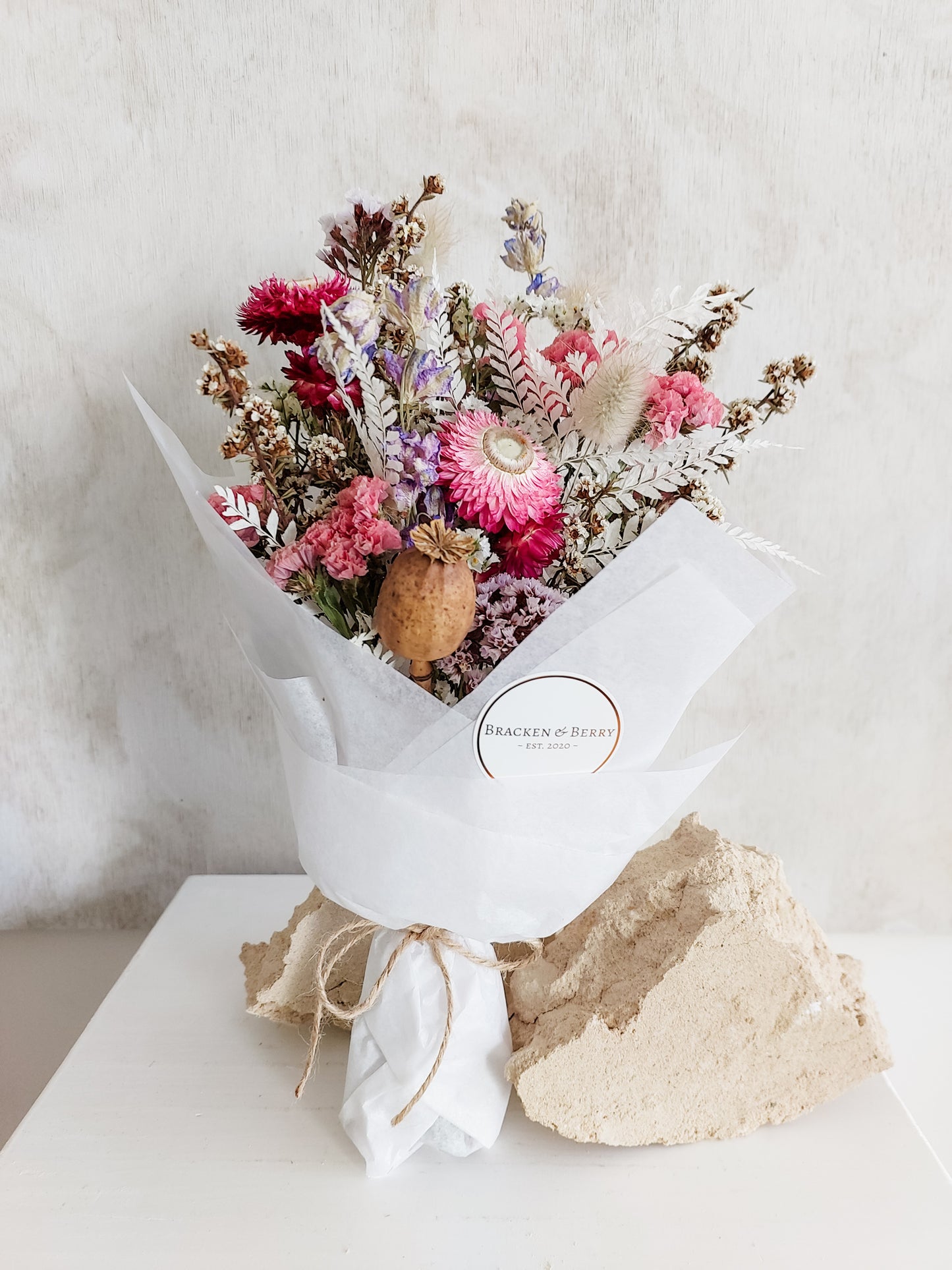 Dried flower posy wrapped in tissue paper - pink and lilac tones.