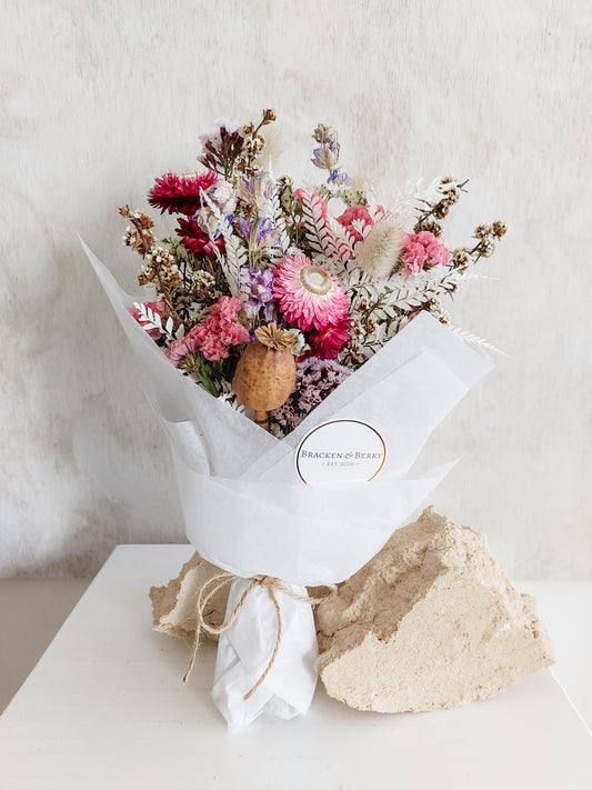 Dried flower posy wrapped in tissue paper - pink and lilac tones.