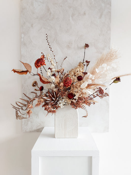 Dried flower arrangement in ceramic vase with autumnal florals – distant full view.