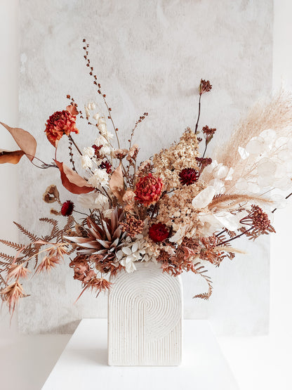 Dried flower arrangement in ceramic vase with autumnal florals – close view.