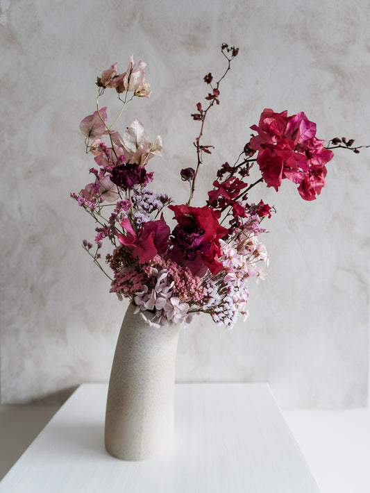 Dried flower arrangement in ceramic vase with deep pink florals – close view.