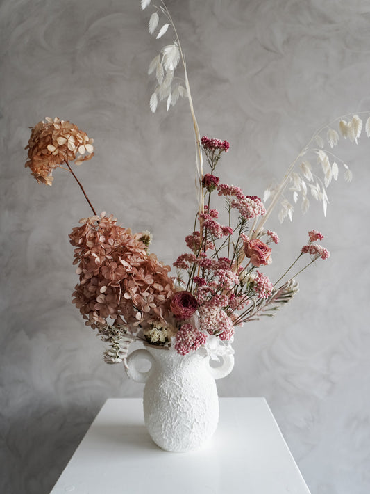 Dried flower arrangement in ceramic urn vase with soft pink florals – close view.