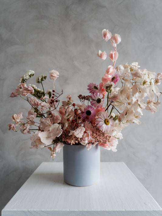Dried flower arrangement in soft blue ceramic vessel with textural pastel florals – close view.