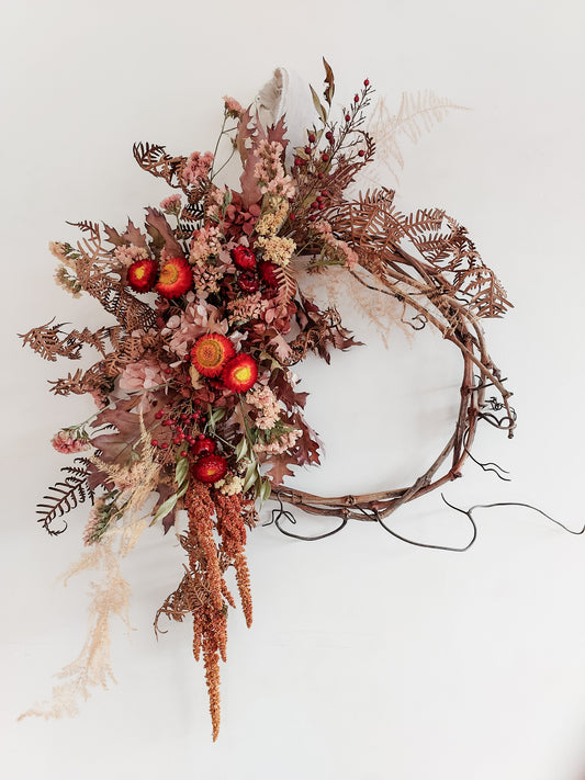 Dried flower wreath in autumnal tones on a grapevine base – close full view.