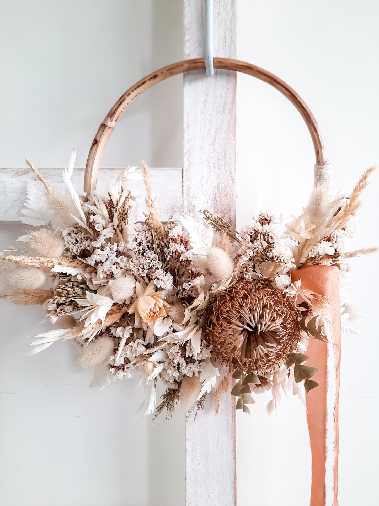 Dried flower wreath in classic neutrals on a small rattan hoop.