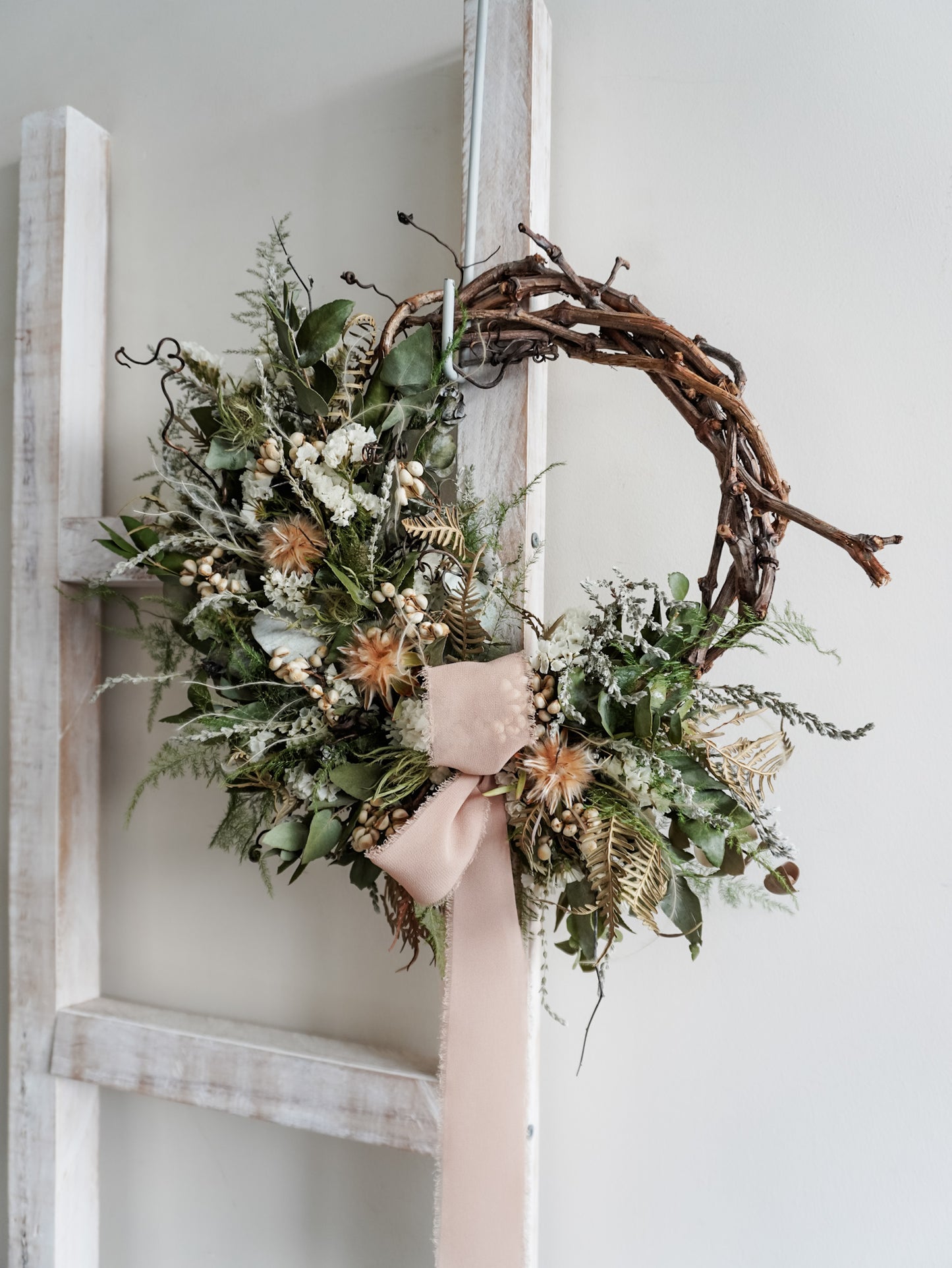 Dried flower wreath in natural Christmas inspired tones on a grapevine base – sidel view.