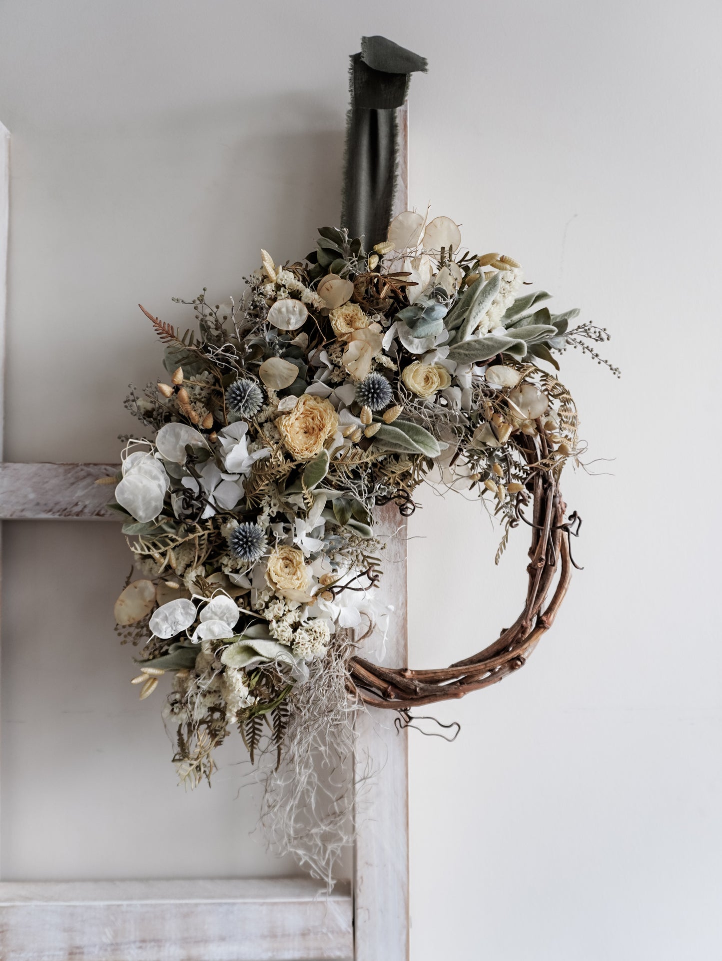 Dried flower wreath in natural tones on a grapevine base – distant full view.