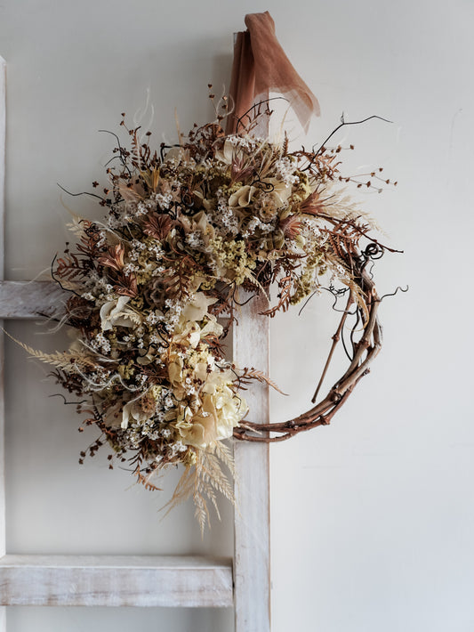 Dried flower wreath in neutral tones boho style on a grapevine base – distant full view.