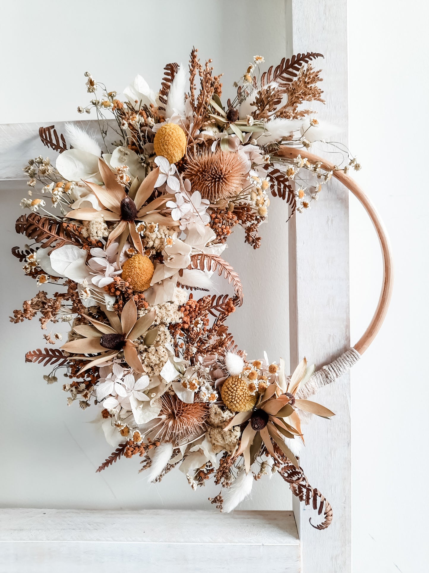 Dried flower wreath in rustic neutrals on a small rattan hoop.