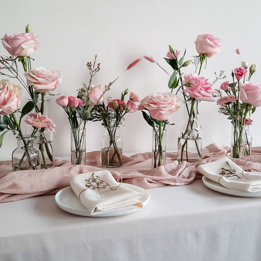 Glass bud vases featuring pink florals with simple table styling.