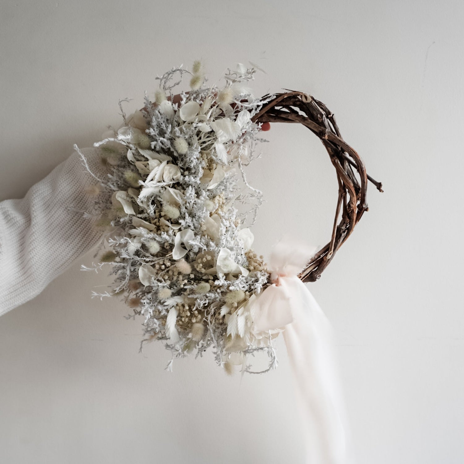 Dried flower wreath in classic White Christmas tones on a grapevine base.