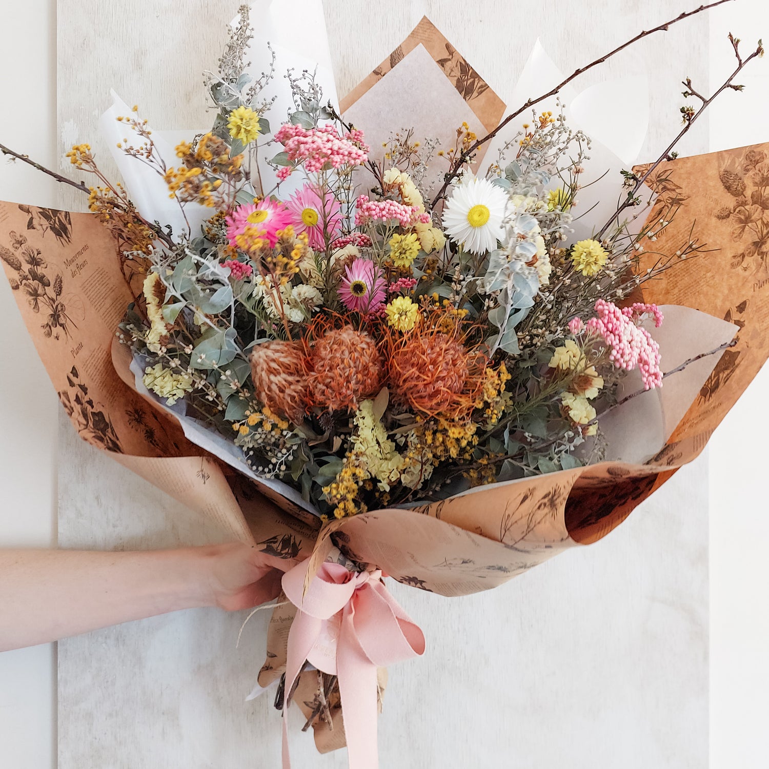 Dried flower bouquet in bright tones wrapped and ready for gifting.