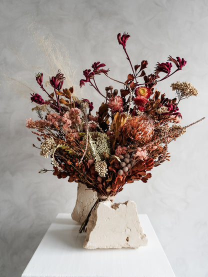 Bouquet of autumnal dried flowers on a white plinth with a grey background - luxe size close view.