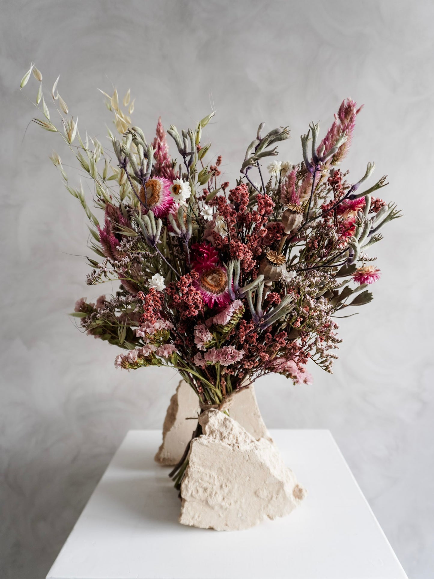 Dried flower bouquet in vibrant colours on a white plinth against a gray background - Classic Size close view.