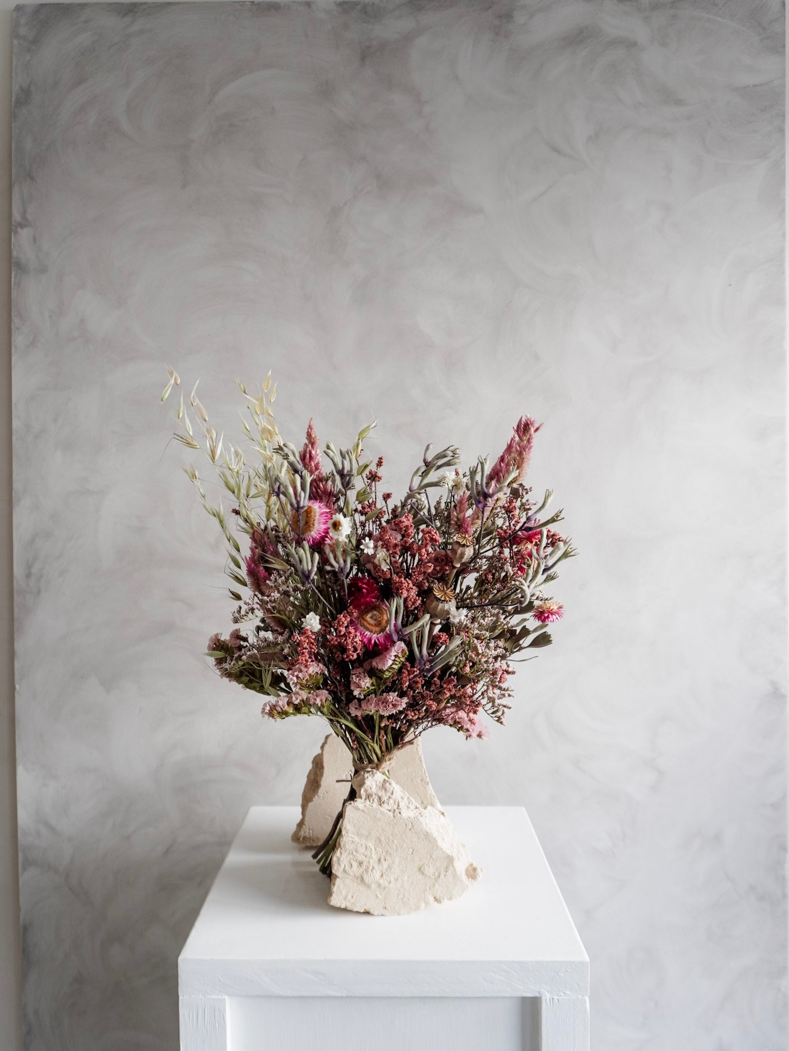 Dried flower bouquet in vibrant colours on a white plinth against a gray background - Classic Size distant view.
