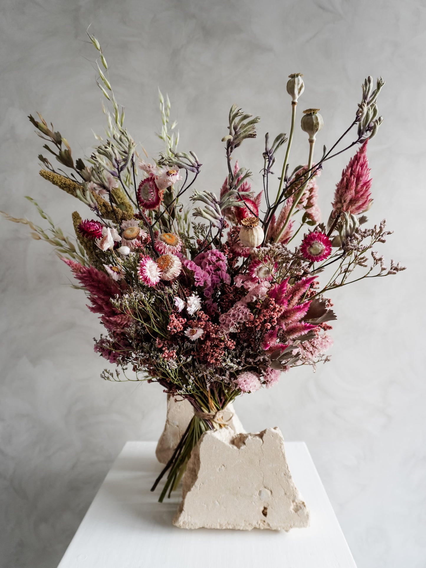 Bouquet of colourful dried flowers on a white plinth against a grey background - luxe size close view.