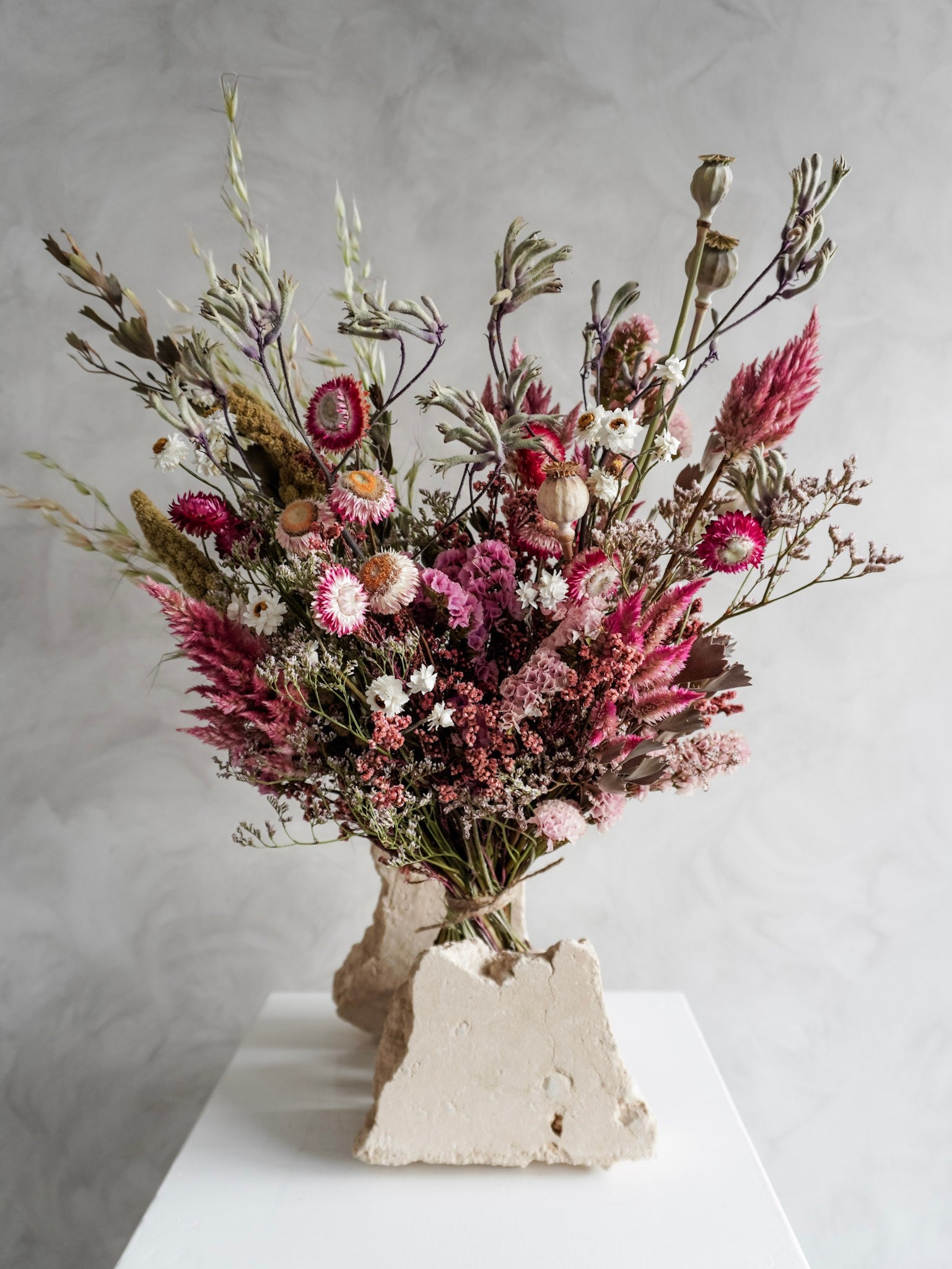 Dried flower bouquet in vibrant colours on a white plinth against a gray background - Luxe Size close view.