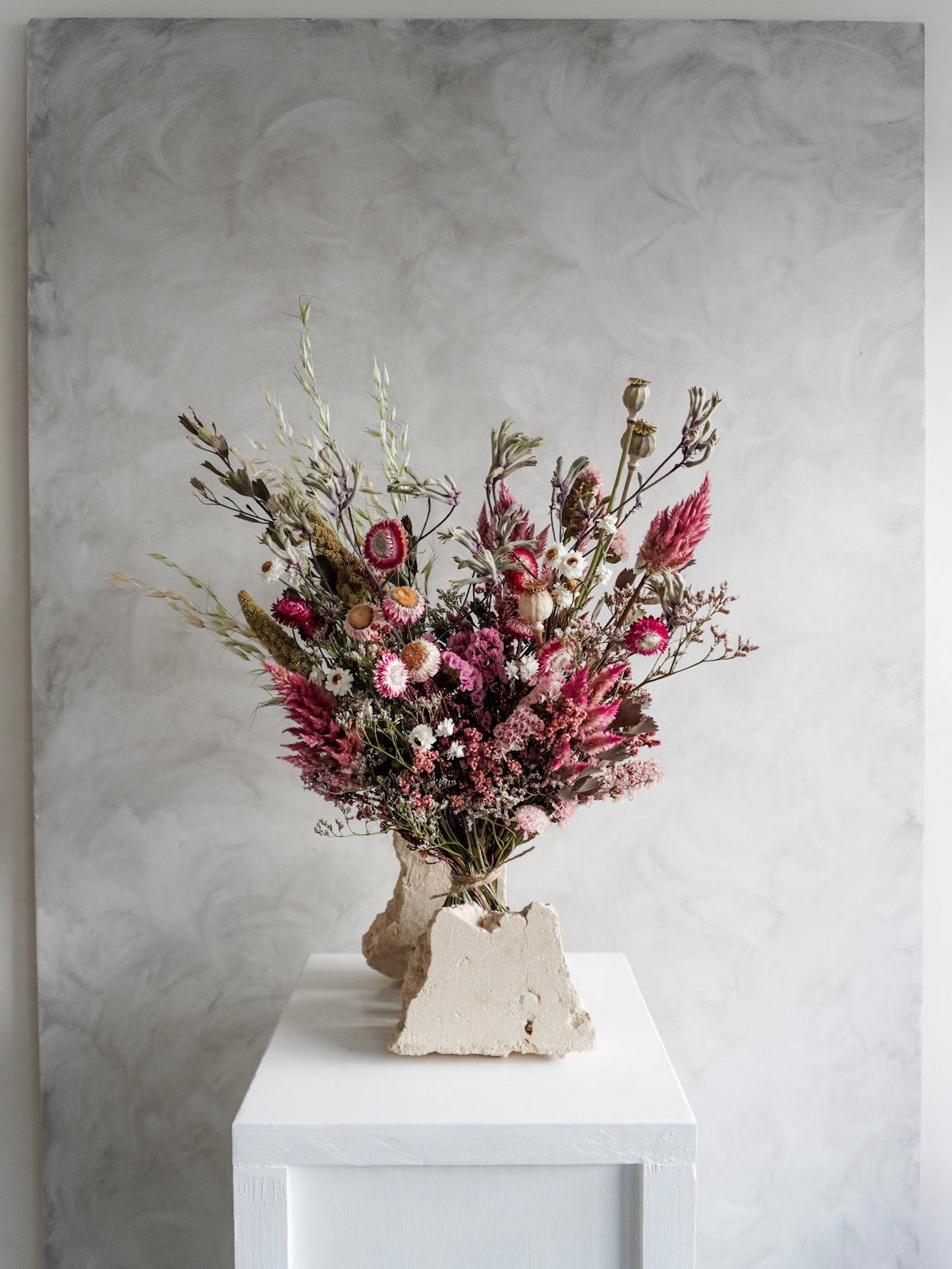 Dried flower bouquet in vibrant colours on a white plinth against a gray background - Luxe Size distant view.