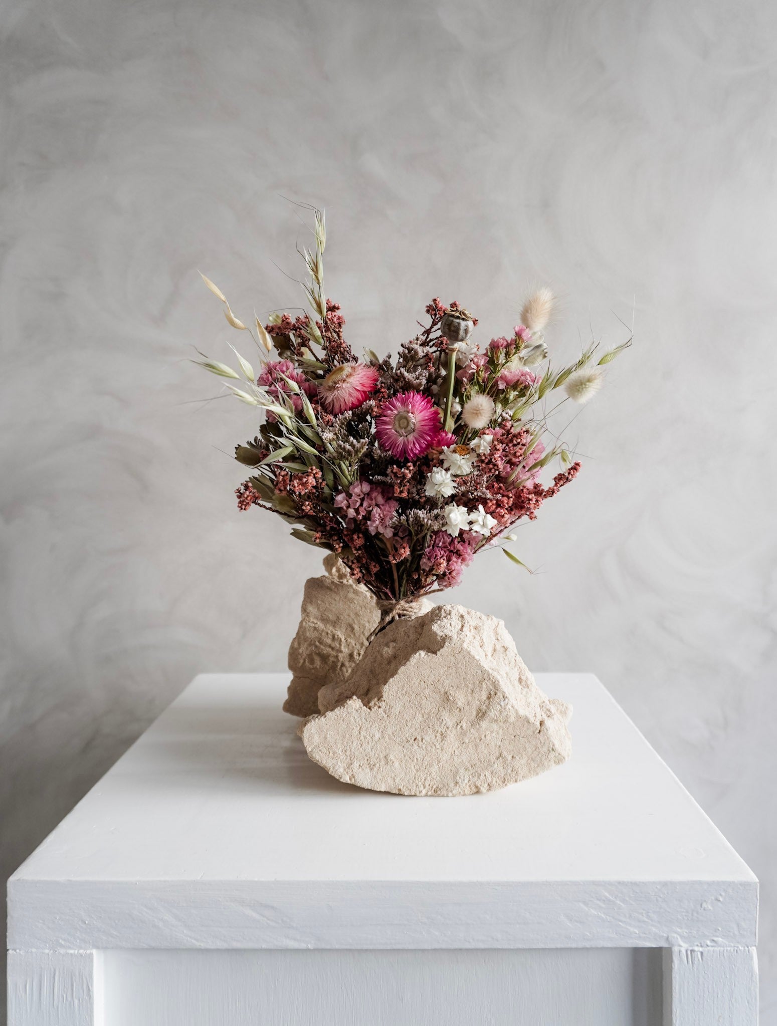 Dried flower bouquet in vibrant colours on a white plinth against a gray background - Posy Size distant view.