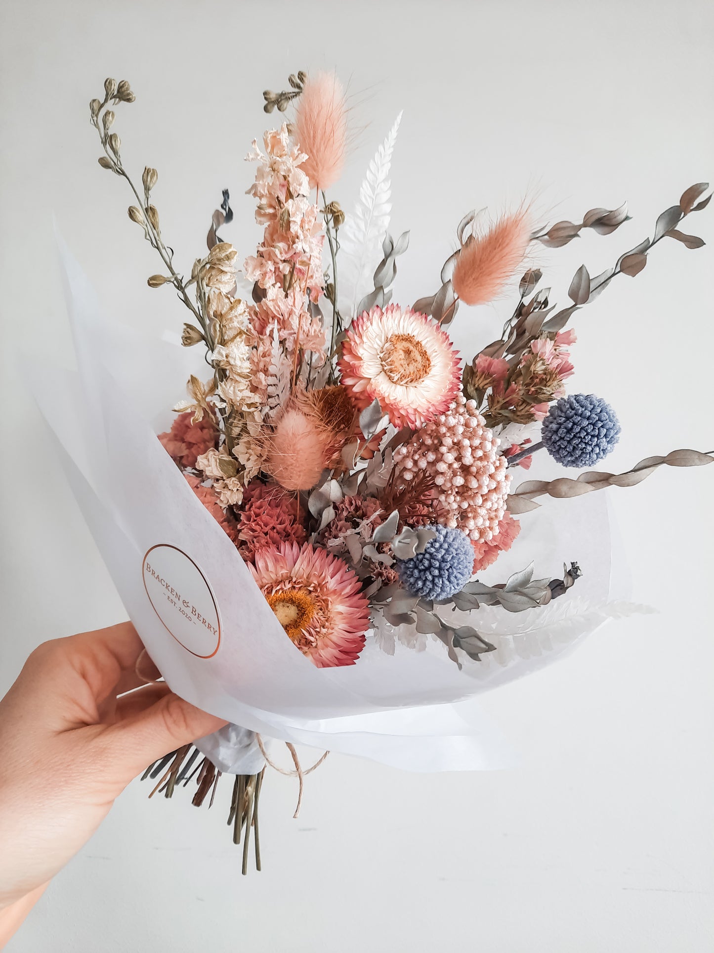 Dried flower posy wrapped in tissue paper - pastel pink and blue tones.