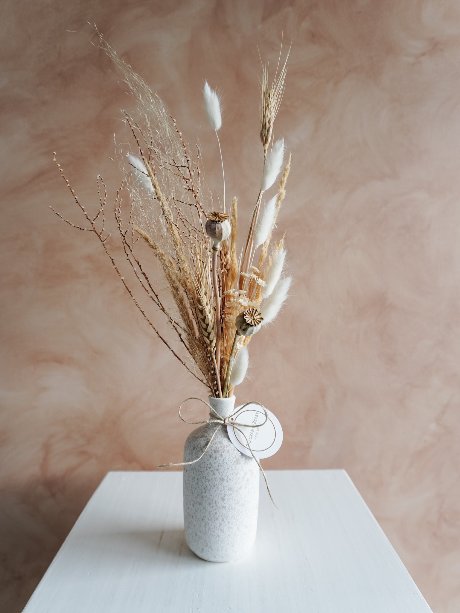 Dried flower arrangement in ceramic bud vase with white and neutral florals – close view.