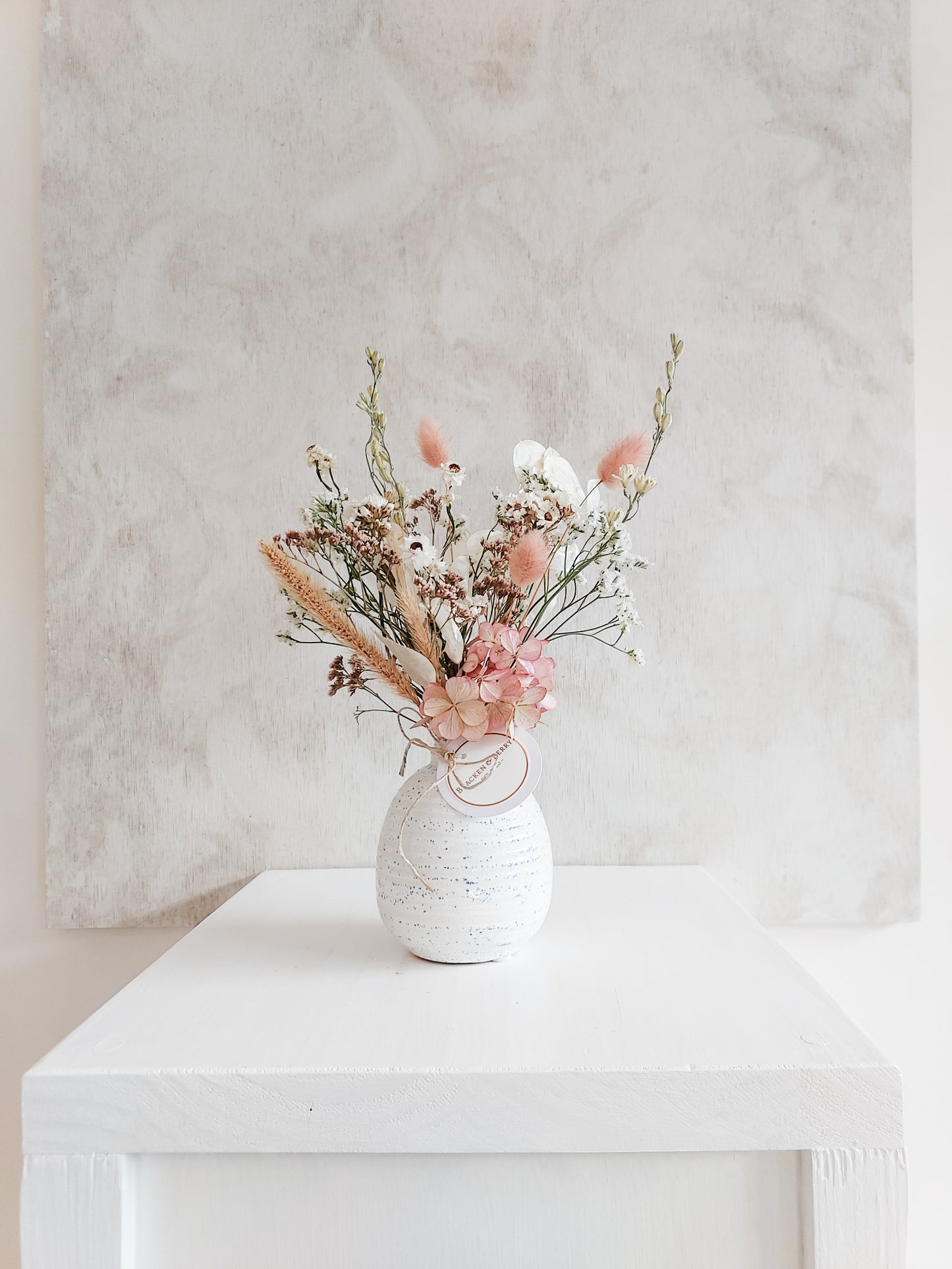 Dried flower arrangement in bud vase with pastel toned florals – distant view.