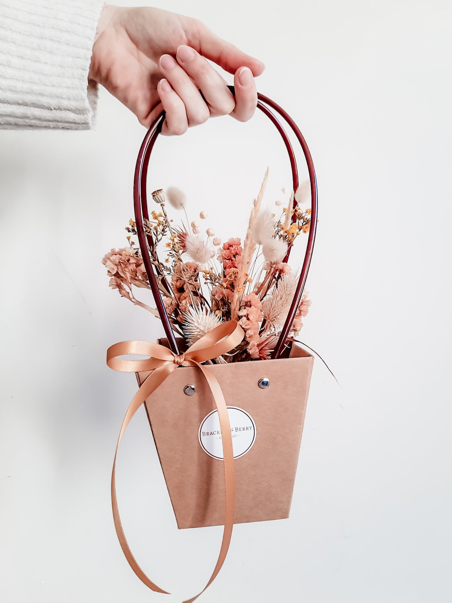 Dried flower arrangement in bud vase with orange florals – vase presented in gift bag.