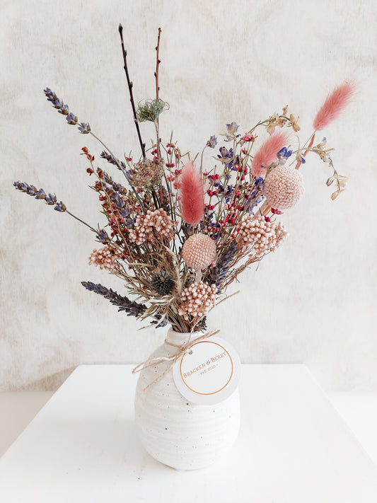 Dried flower arrangement in bud vase with purple florals – close full view.