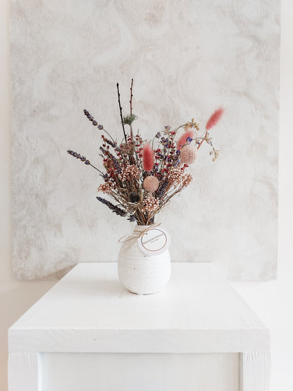 Dried flower arrangement in bud vase with purple florals – distantl view.