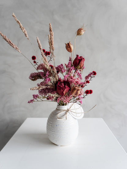 Dried flower arrangement in ceramic bud vase with pink and red  florals – close view.