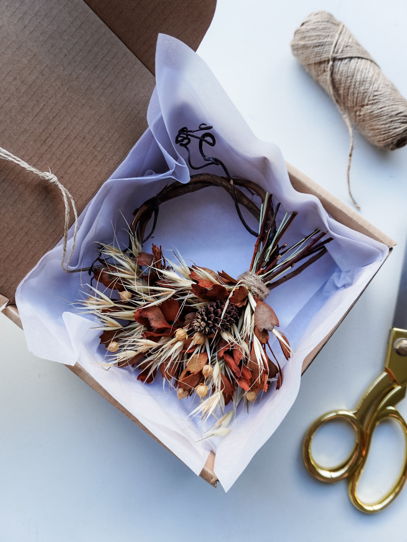 Dried flower mini wreath decoration in earthy tones on a grapevine base presented in a box ready for gifting.