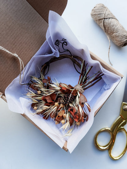Dried flower mini wreath decoration in earthy tones on a grapevine base presented in a box ready for gifting.
