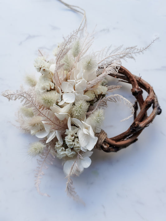 Dried flower mini wreath decoration in soft pink and white tones on a grapevine base – close full view.