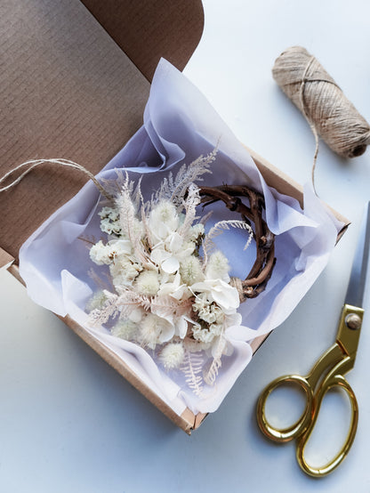 Dried flower mini wreath decoration in soft pink and white tones on a grapevine base presented in a box ready for gifting.