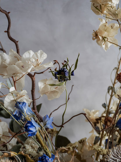 Close-up of dried flowers and branches against a neutral background.