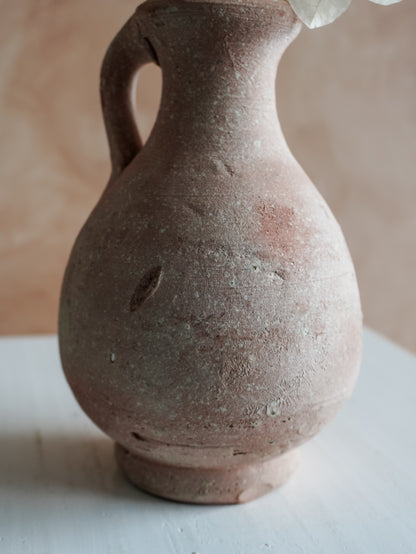 Terracotta vase against a soft pink background.