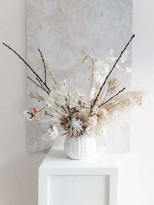 Dried flower arrangement in ceramic vase with neutral florals – distant view.