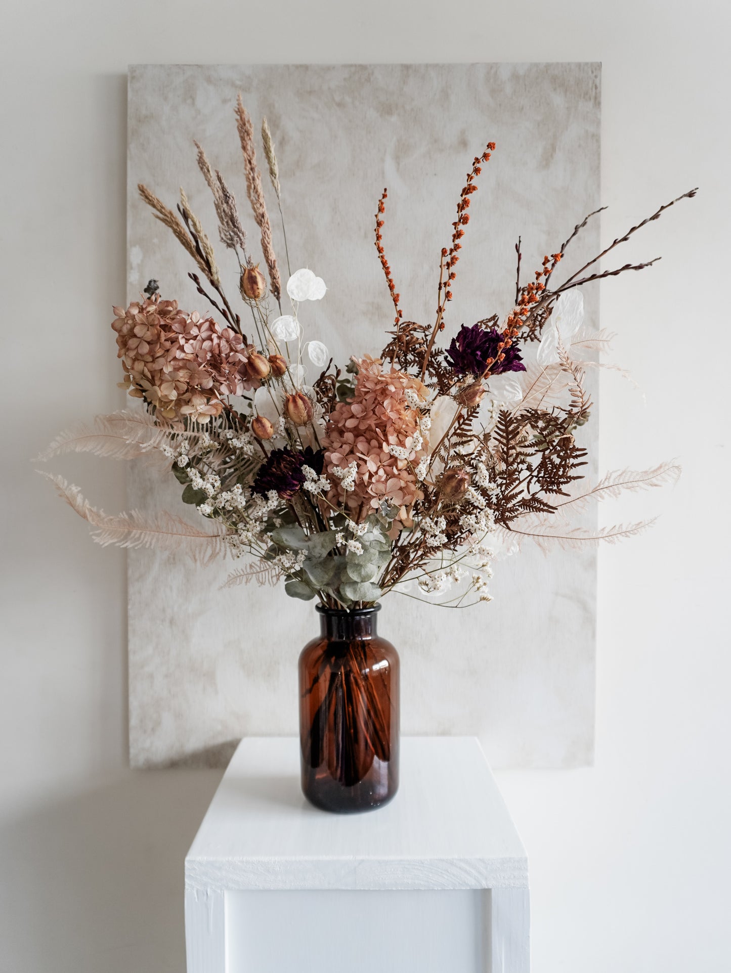 Dried flower arrangement in amber bottle with pastel florals – full view.