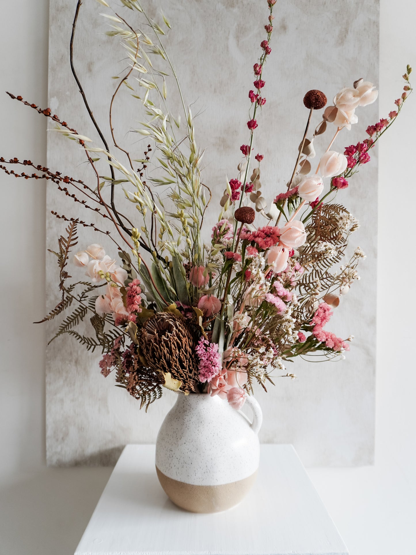 Dried flower arrangement in ceramic jug vase with soft pink florals – close view.