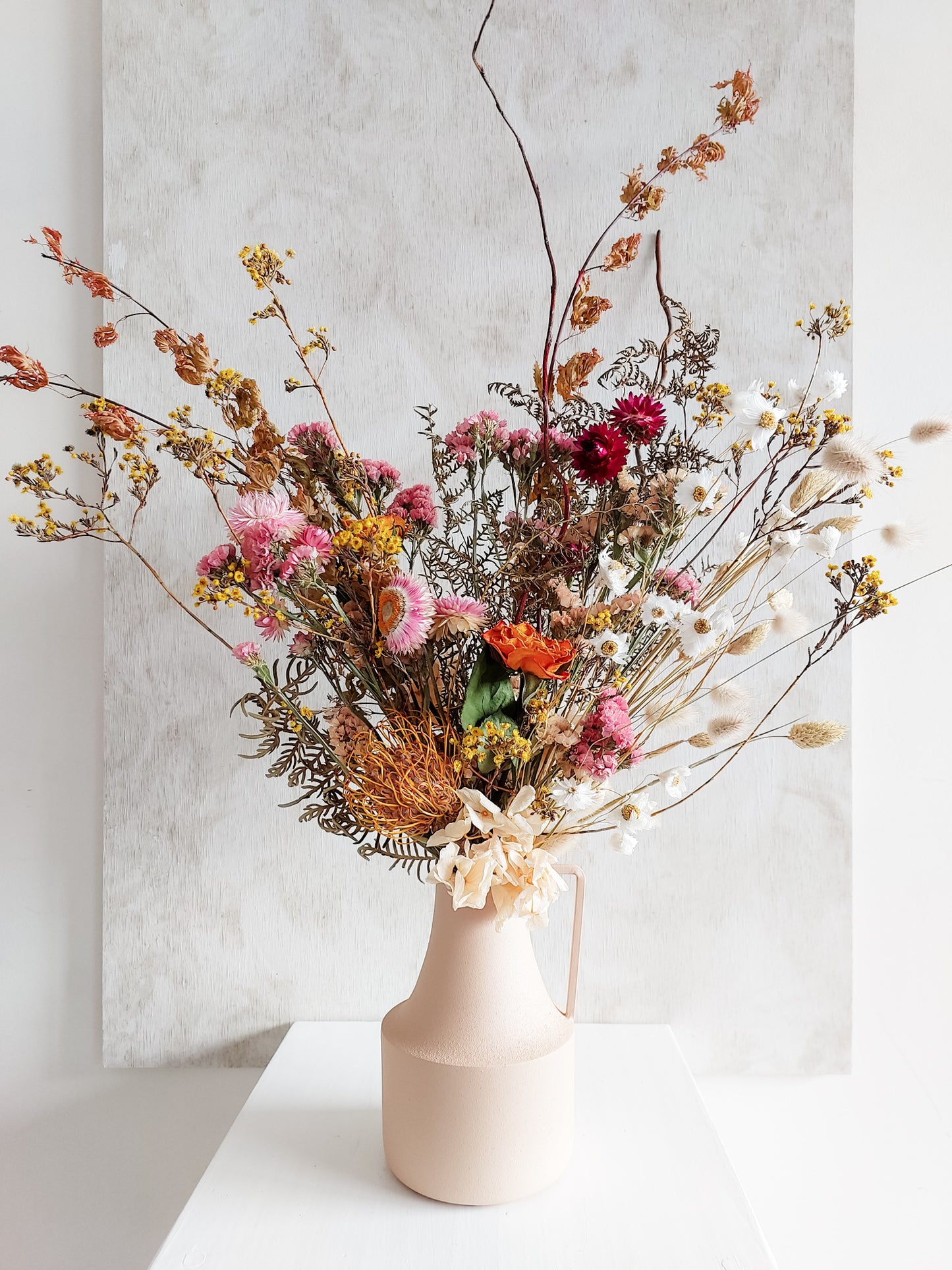 Dried flower arrangement in metal vase with bright colourful florals – close view.