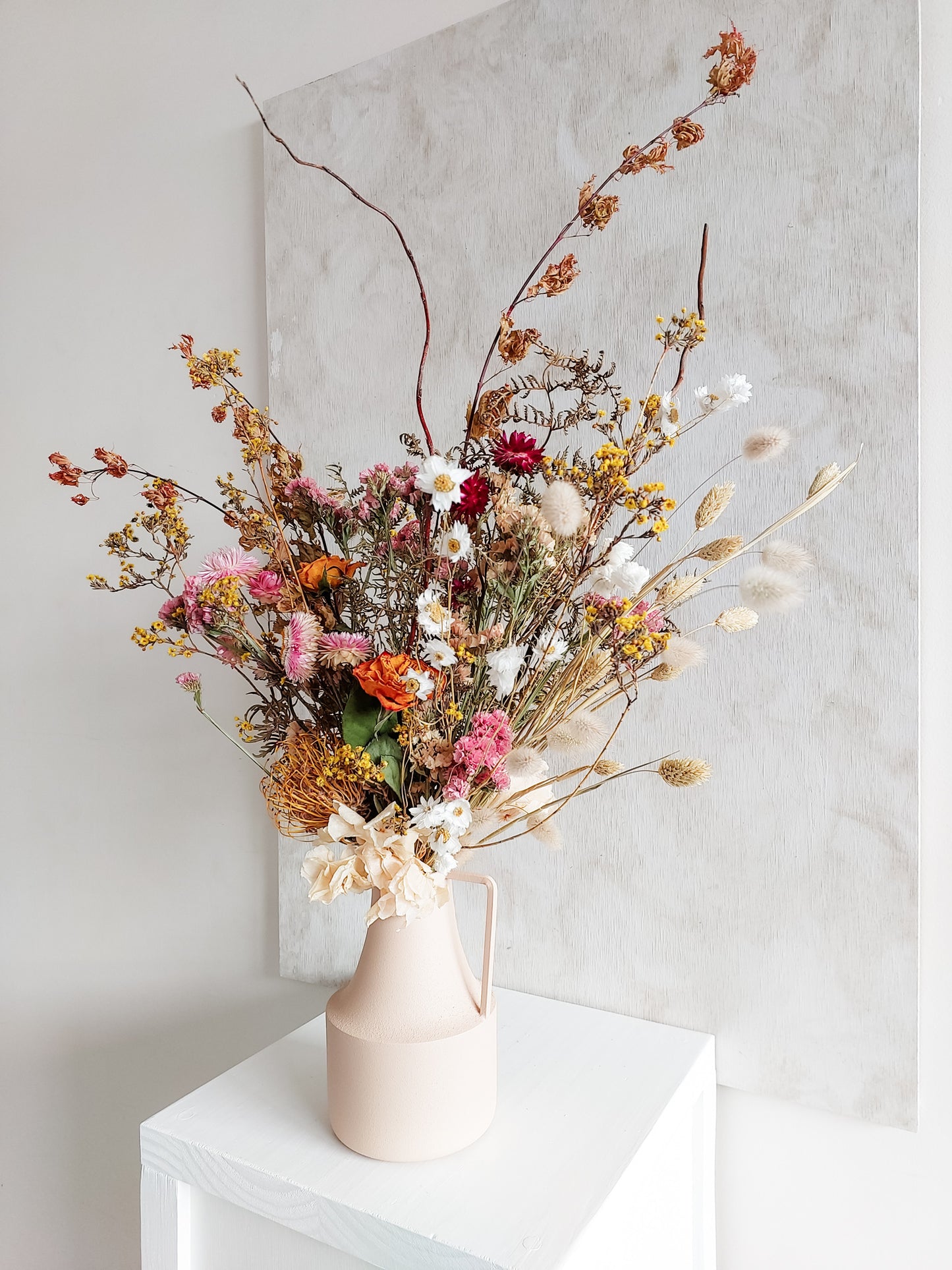 Dried flower arrangement in metal vase with bright colourful florals – side view.