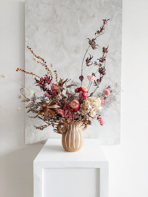 Dried flower arrangement in ceramic urn vase with rich berry tone florals – full view.