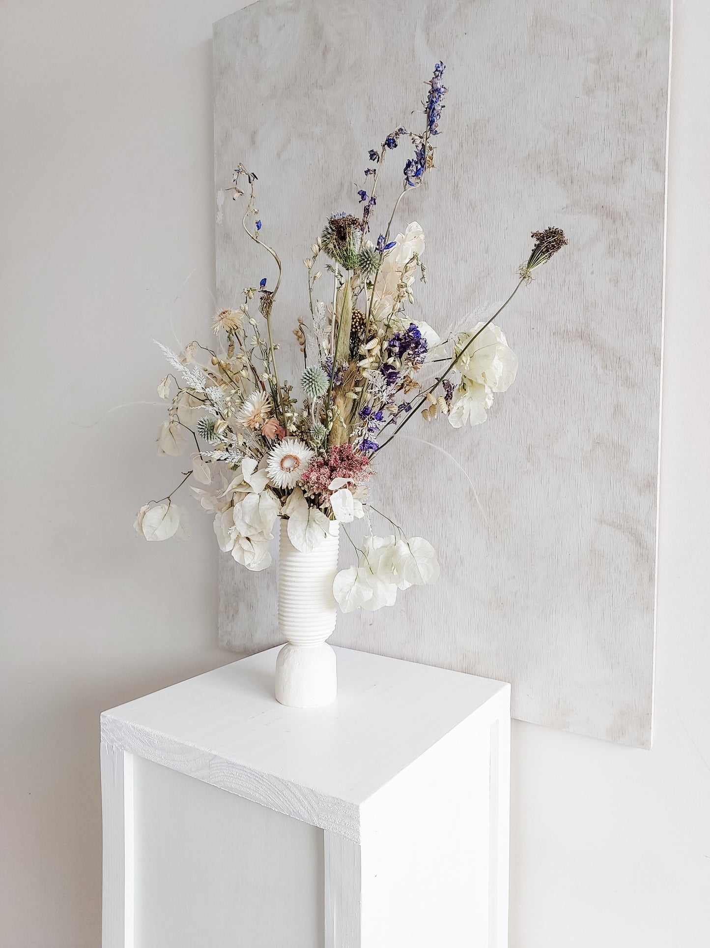 Dried flower arrangement in ceramic vase with whimsical florals – right angle view.