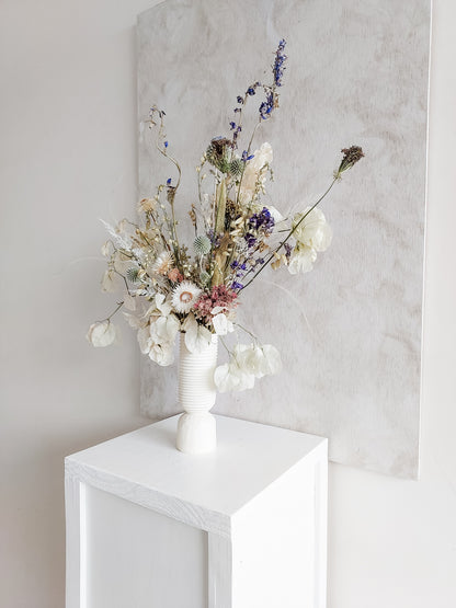 Dried flower arrangement in ceramic vase with whimsical florals – right angle view.