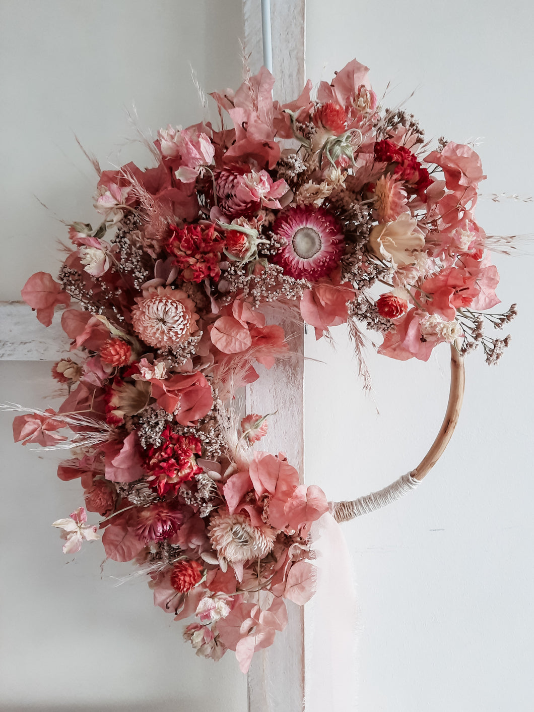 Dried flower wreath in berry tones on a rattan hoop base – close full view.